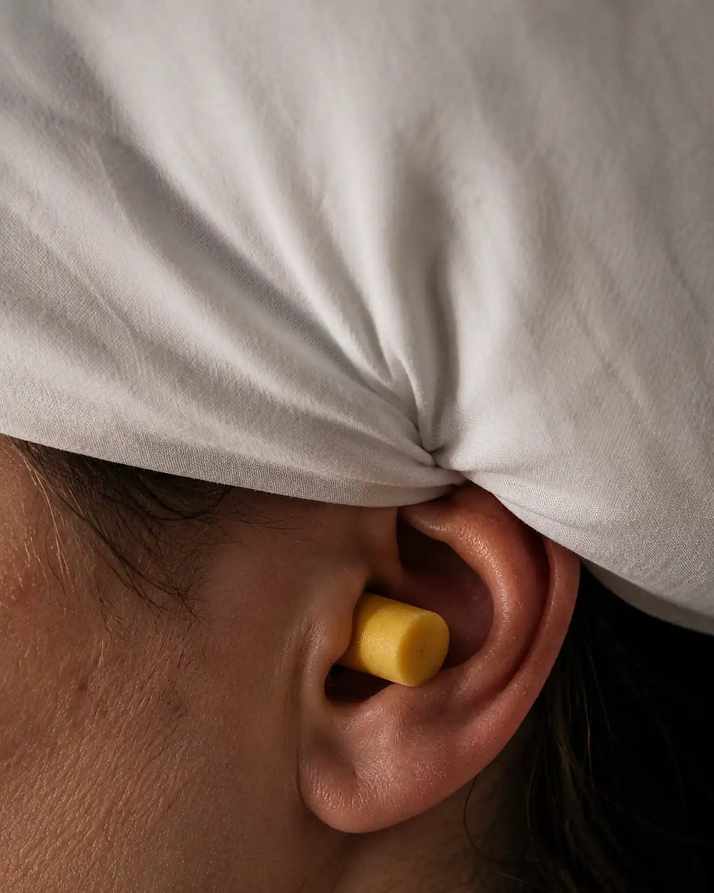 Un tapón de espuma que sobresale de la oreja y deforma la almohada