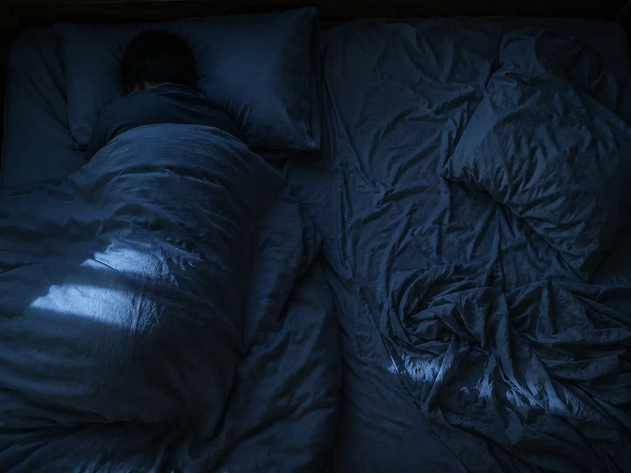 Cama matrimonial vista desde arriba: un lado quieto, el otro con las sábanas revueltas