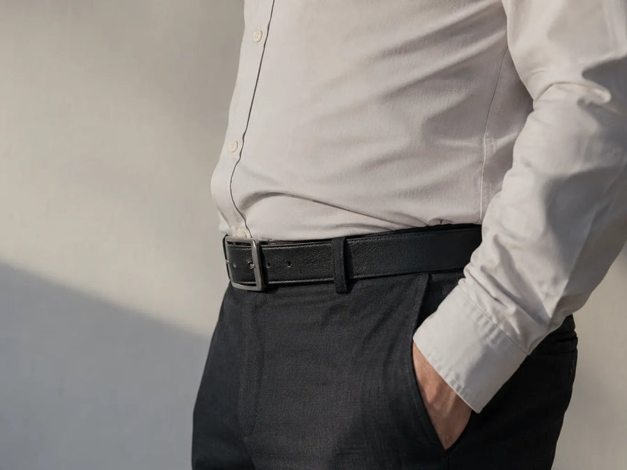Perfil de la cintura con camisa fajada y el bulto de la hebilla levantando la tela